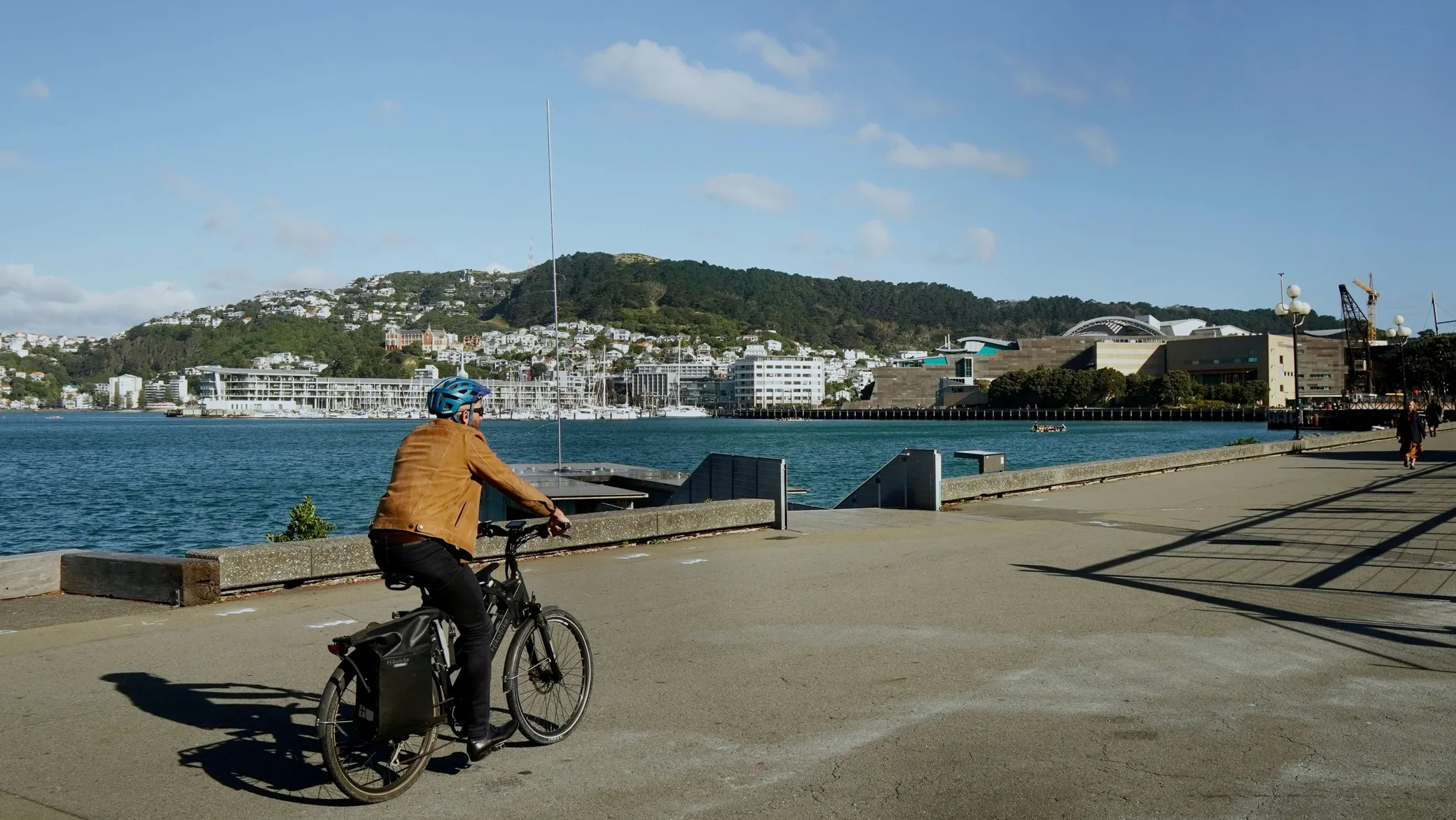 A person in casual clothes biking on an e-bike along the Wellington waterfront