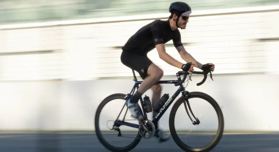 A man wearing black lycra cycling fast with motion blur
